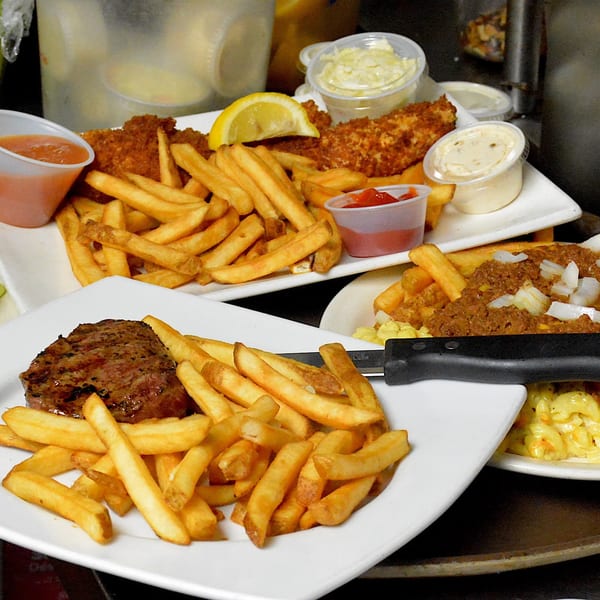 Plates of steak and fries, fish and chips, and chili cheese fries from Elmwood Inn.