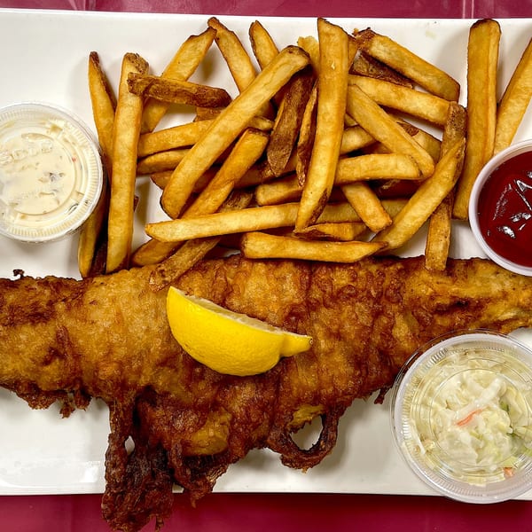 Elmwood Inn's fish and chips with tartar sauce, ketchup, coleslaw, and a lemon wedge.
