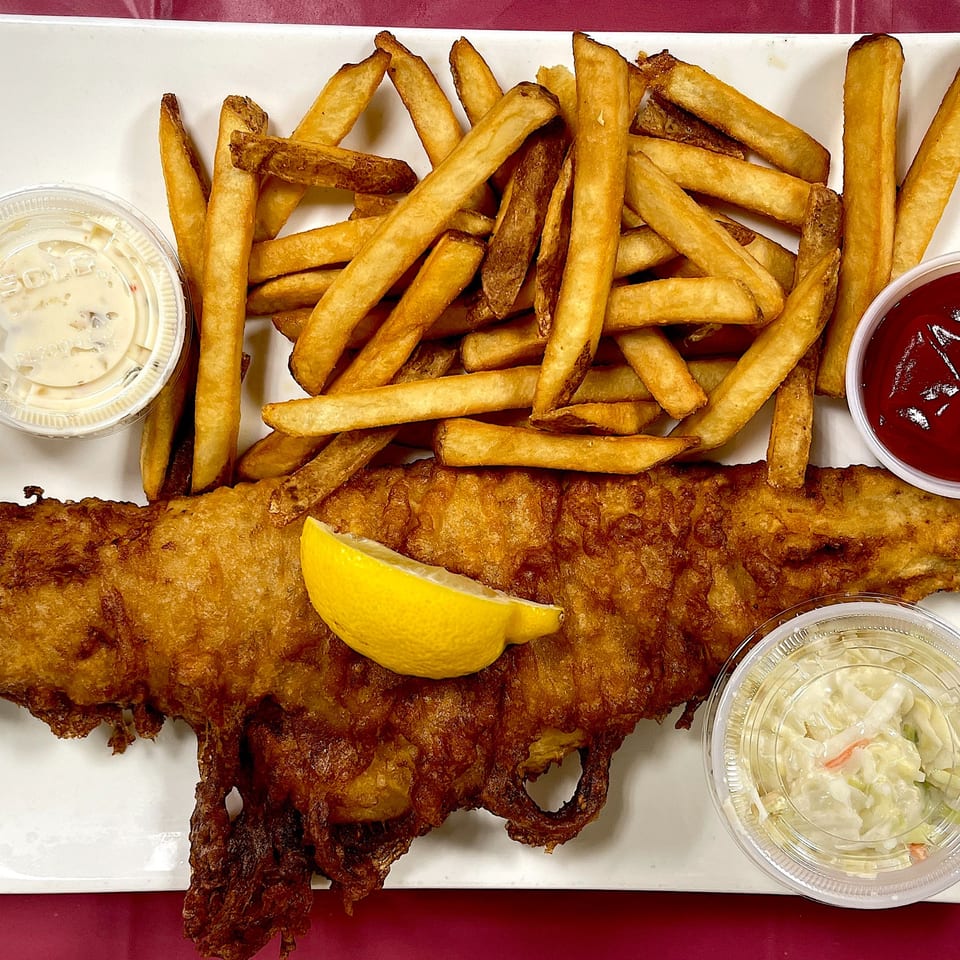 Elmwood Inn's fish and chips with tartar sauce, ketchup, coleslaw, and a lemon wedge.